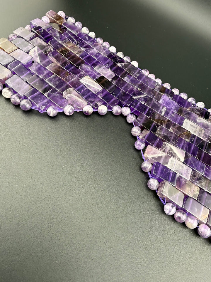 Natural amethyst crystal eye mask with polished gemstone tiles and beads displayed on a dark background for relaxation, meditation, and spa wellness.
