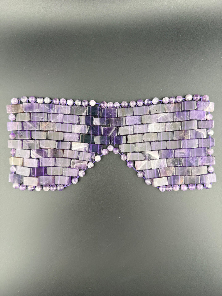 Natural amethyst crystal eye mask displayed on a dark background for cooling relaxation, meditation, energy healing, and luxury spa self-care.