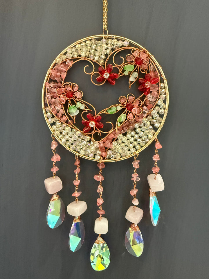 Handcrafted Tree of Life crystal suncatcher featuring natural rose quartz gemstones, pink floral wire art, faceted crystal prisms, and gold wire wrapped design. A beautiful spiritual window hanging that brings light, love, and positive energy into any space.