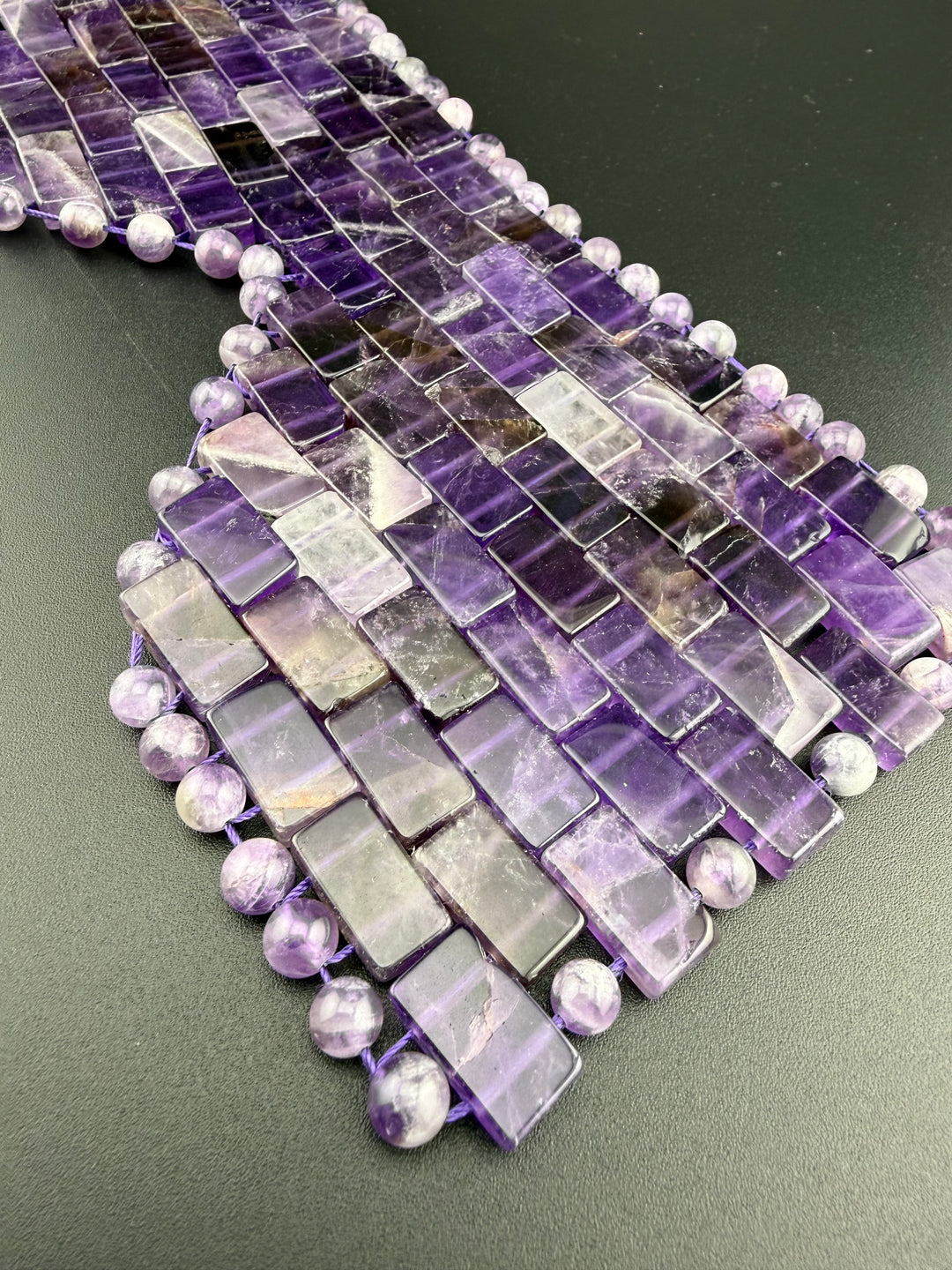 Natural amethyst crystal eye mask with polished gemstone tiles and beads displayed on a dark background for cooling relaxation, meditation, and spa self-care.