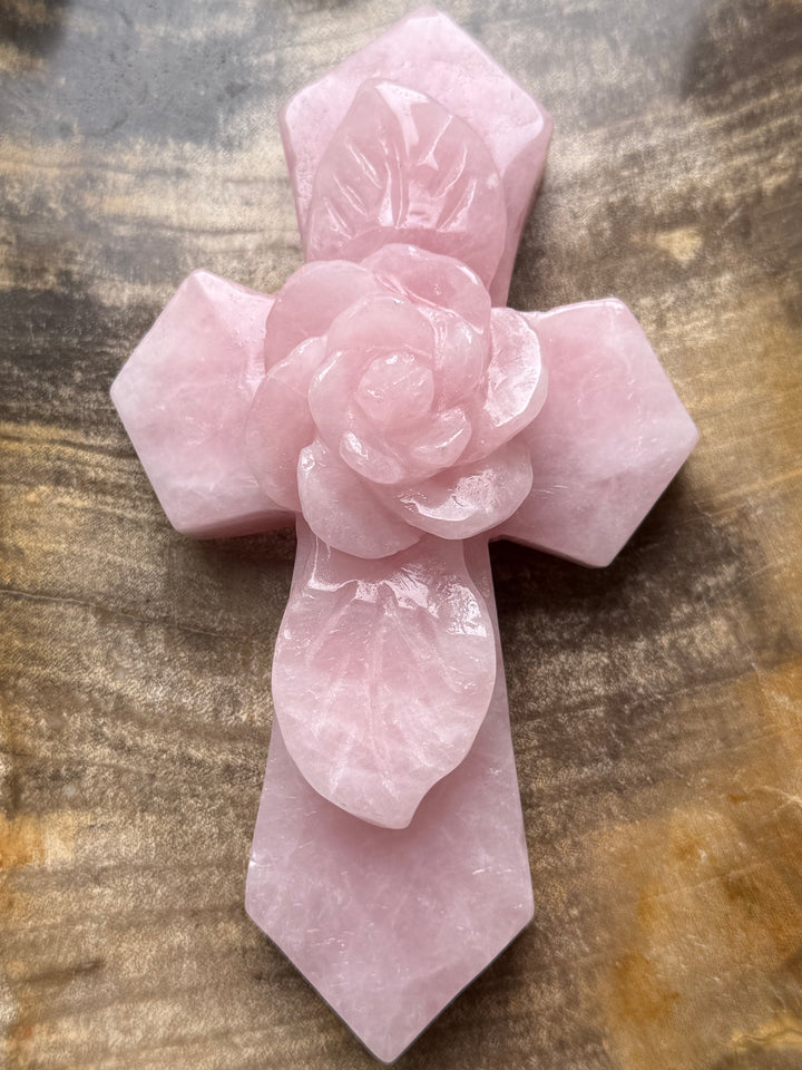 Large natural rose quartz crystal cross with an intricately carved pink rose centerpiece, symbolizing unconditional love, faith, and compassion.