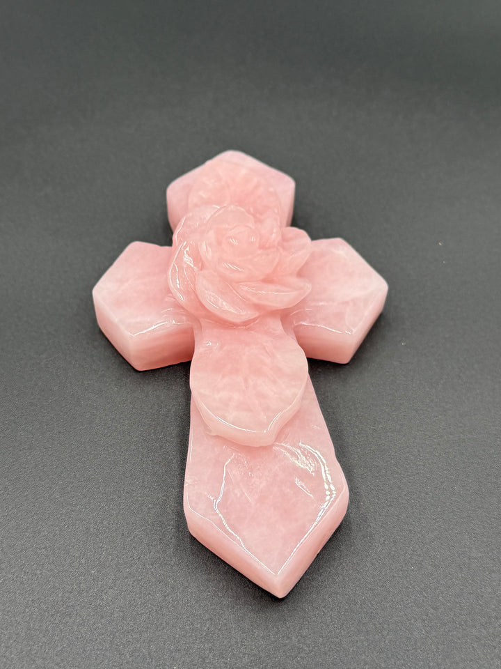 Polished rose quartz cross with a carved floral centerpiece, a meaningful crystal gift for someone who appreciates faith and natural gemstones.